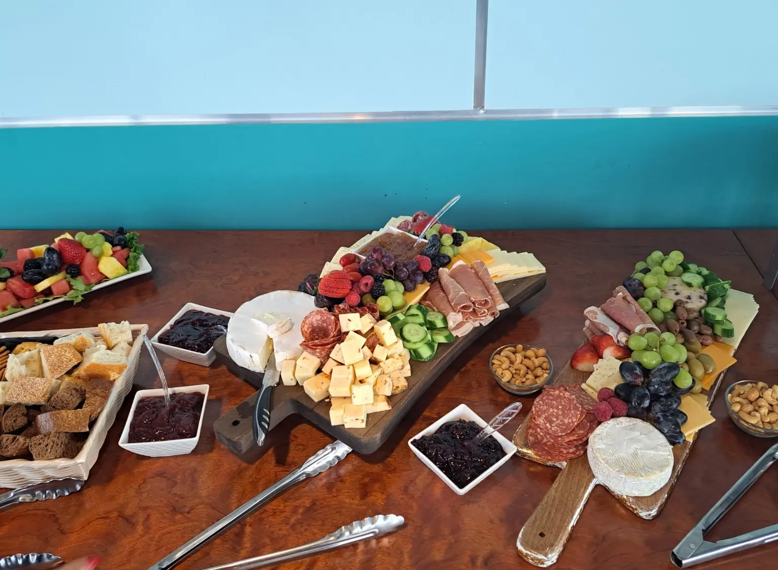 A catering display with charcuterie boards, fruit, cheese, breads, nuts, and preserves